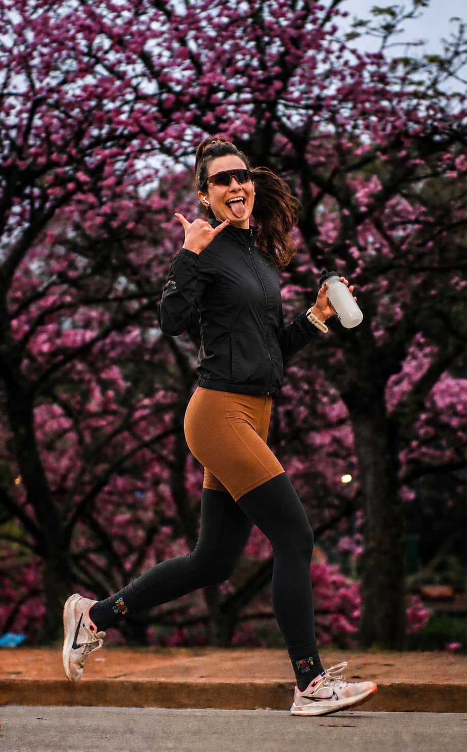 Marina correndo com árvores cor-de-rosa ao fundo